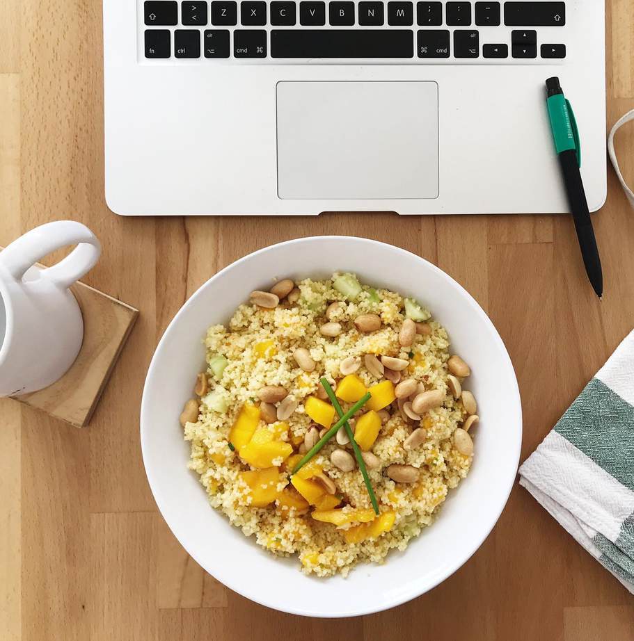 Cuenco de cuscús junto a un portátil: almuerzo saludable en el puesto de trabajo
