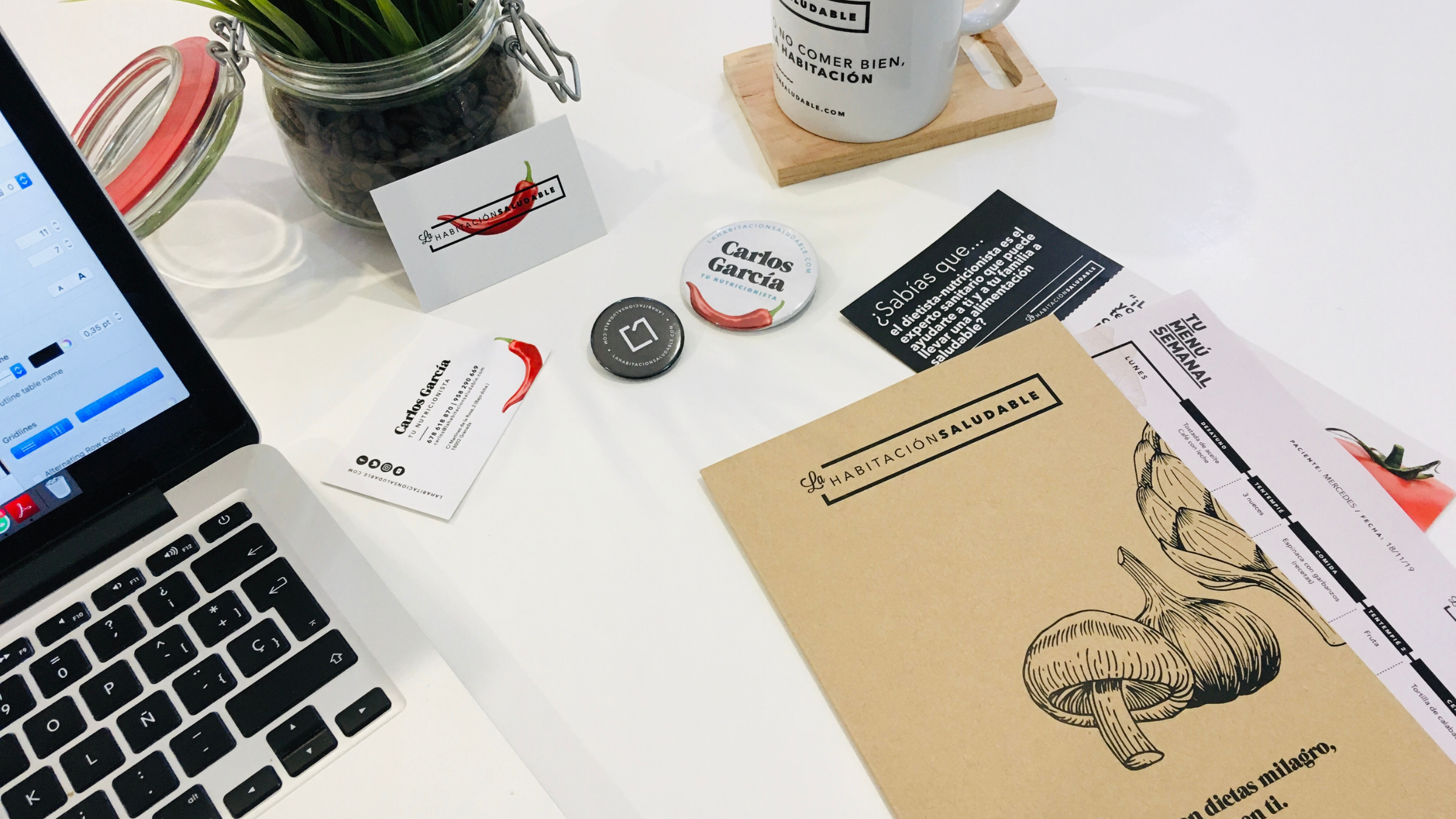 Mesa de trabajo de La Habitación Saludable con tarjetas, chapas y material de marca