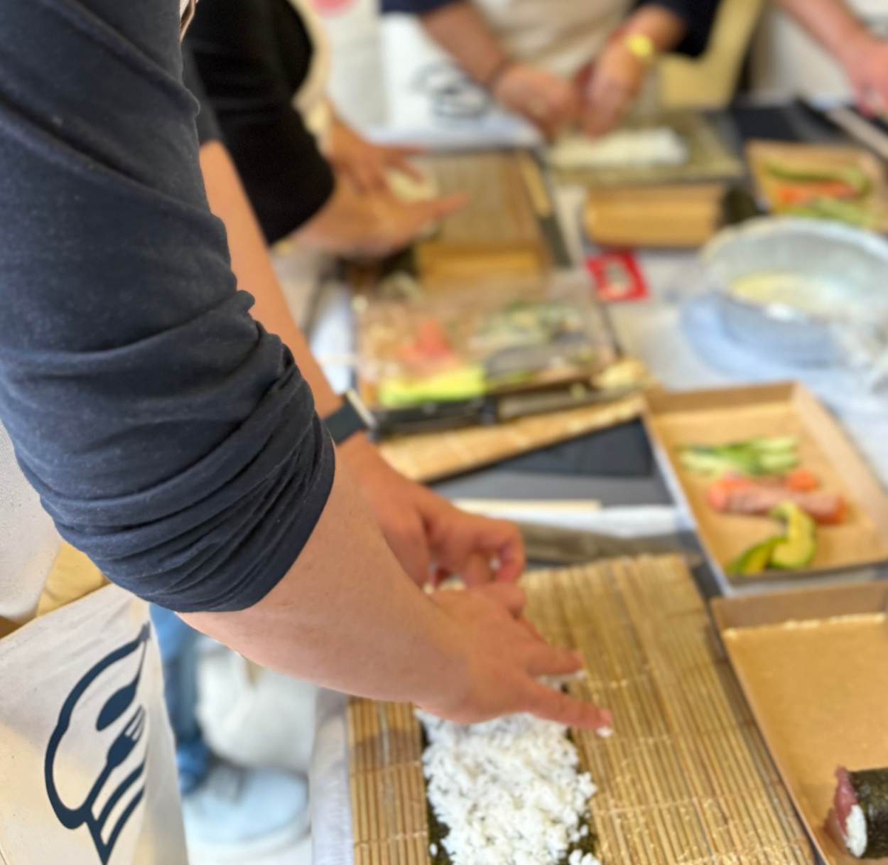 Manos preparando sushi en un taller de team building corporativo